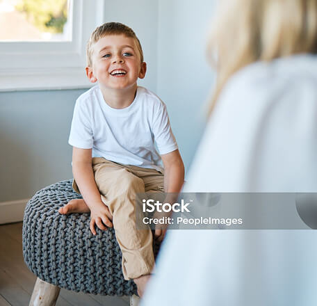 Photo of a boy smiling at a therapist who is facing away from camera