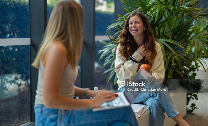 Photo of two young women talking and smiling at each other