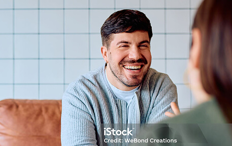 Man sat facing a woman, smiling at her