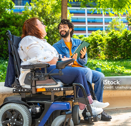 Photo of a woman in a wheelchair talking and smiling with a man