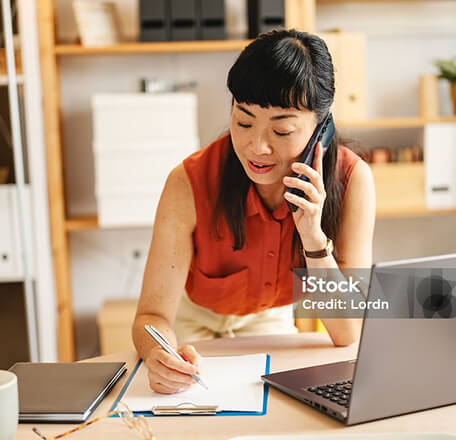 A woman on a phone call, taking notes