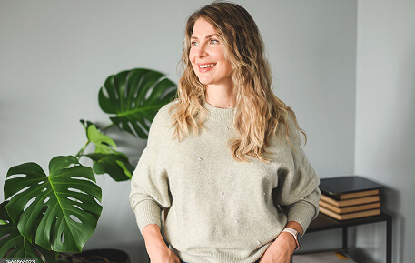 A woman, standing, smiling away from the camera